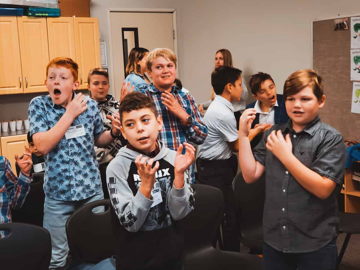 Kid's Ministry engaging in a classroom activity, clapping and showing surprised expressions.