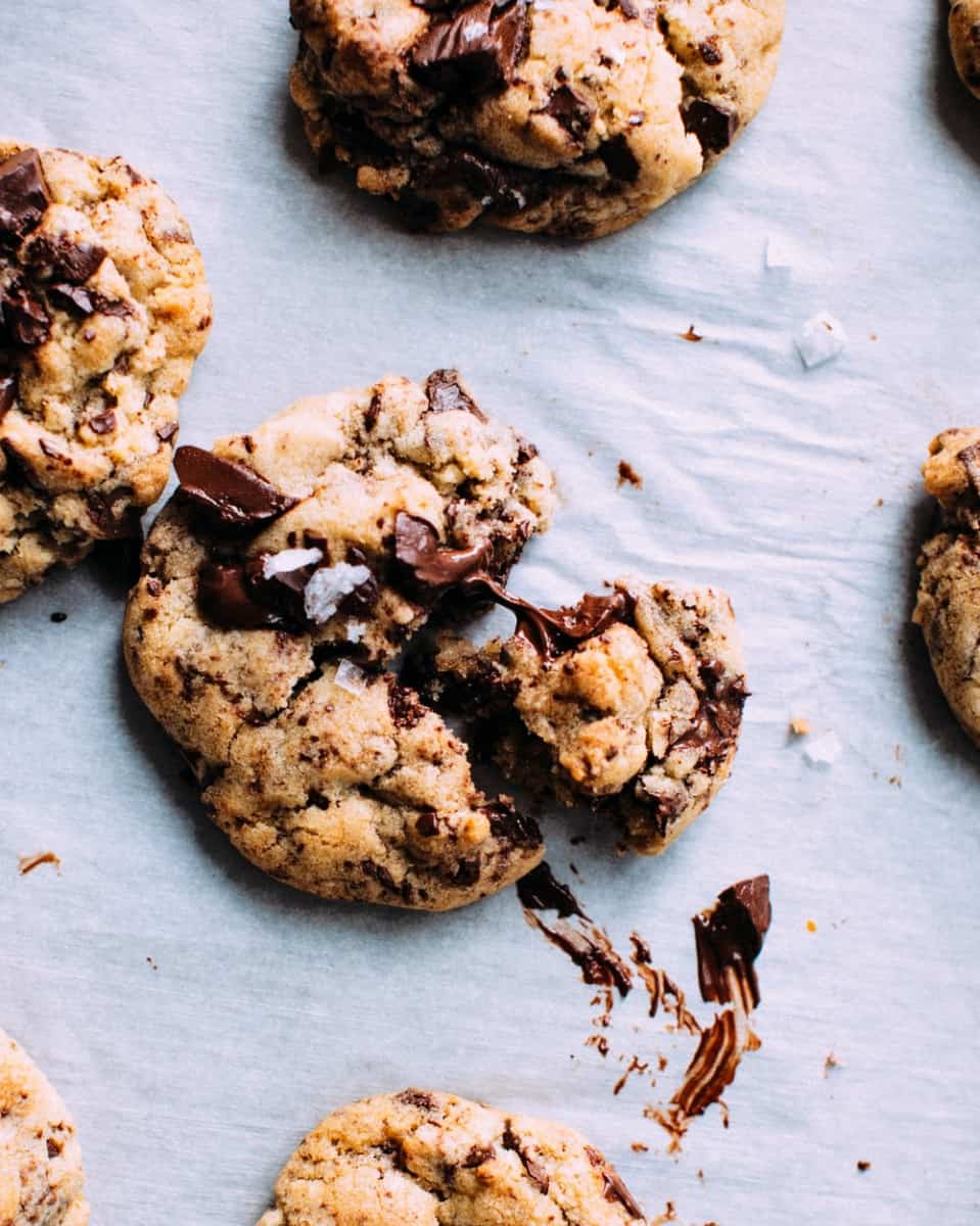 Freshly baked chocolate chip cookies with sea salt, some cookies broken, prepared by the Dream Team volunteers, on a parchment-lined baking sheet.