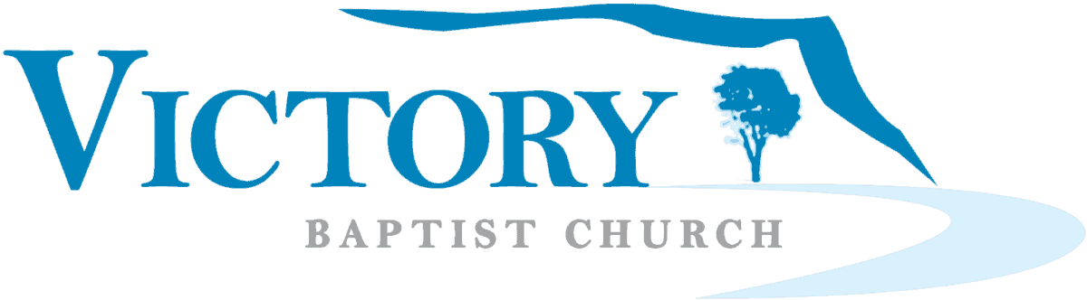 Logo of Victory Baptist Church featuring the text "Victory" in large letters and "Baptist Church" below it, with a tree and a curved path intertwined among vibrant leaves in the background.