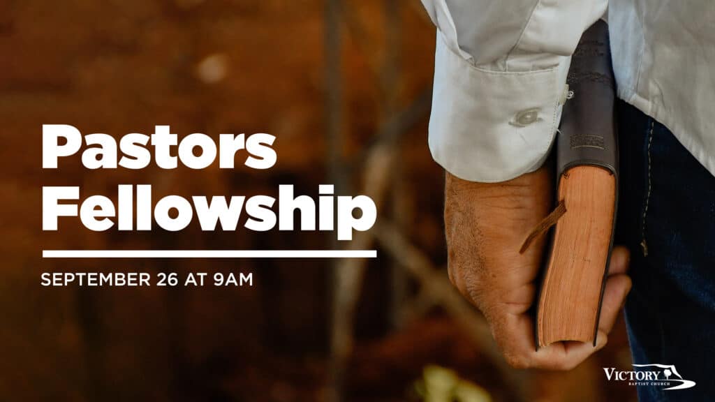 Close-up of a person's hand holding a leather-bound book, with text on the left reading "Pastors Fellowship, September 26 at 9AM." The Victory Church logo is visible in the bottom right corner.