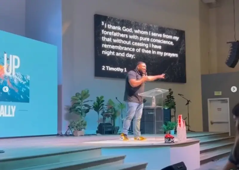 Young people gathered at a youth rally listening to a preacher onstage.